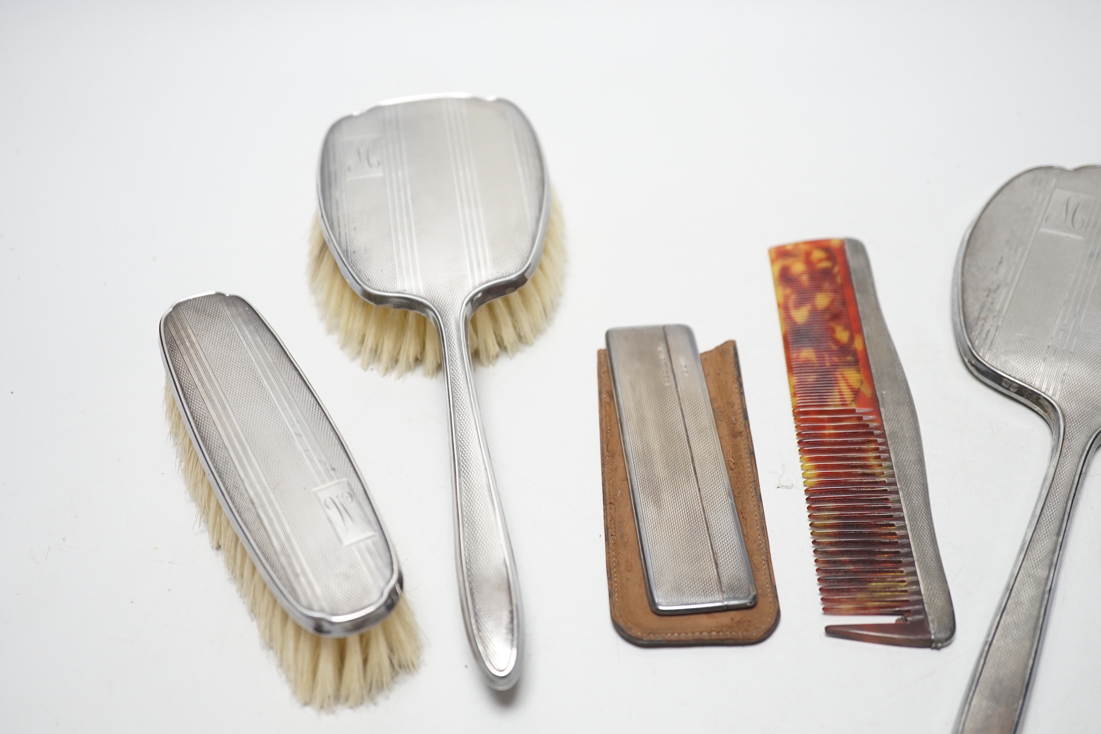A George V silver backed four piece dressing table set, Birmingham, 1934 and one other silver cased comb.